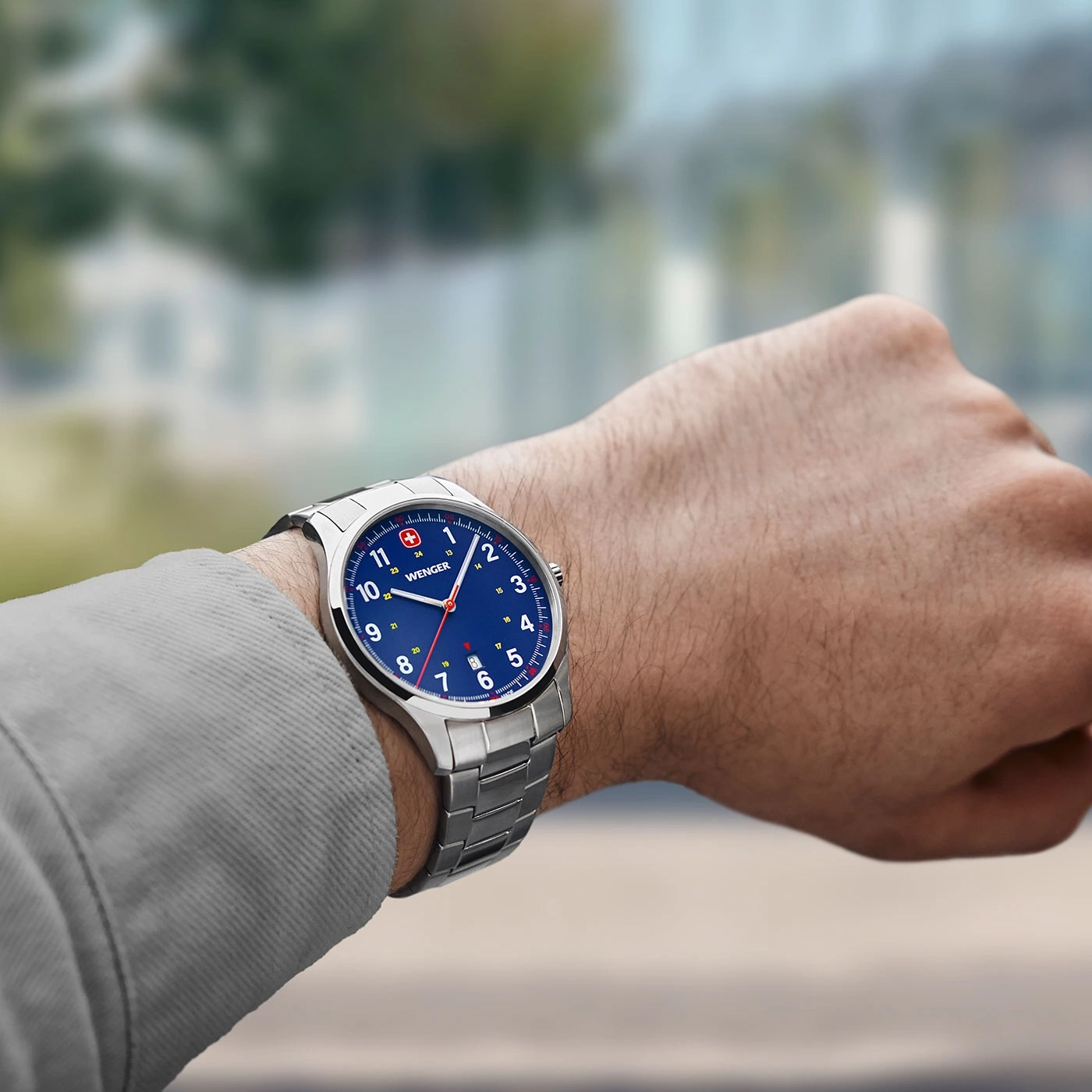Wristwatch on wrist, blue dial, silver band, Wenger brand, close-up shot, time