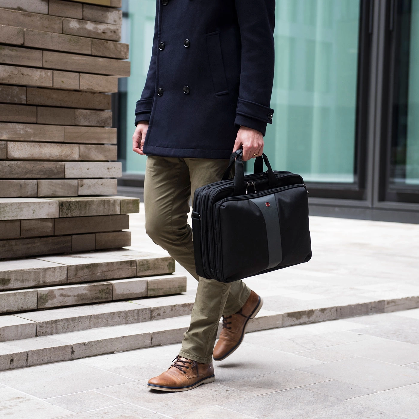 Man in coat holding a black briefcase walking down the street.