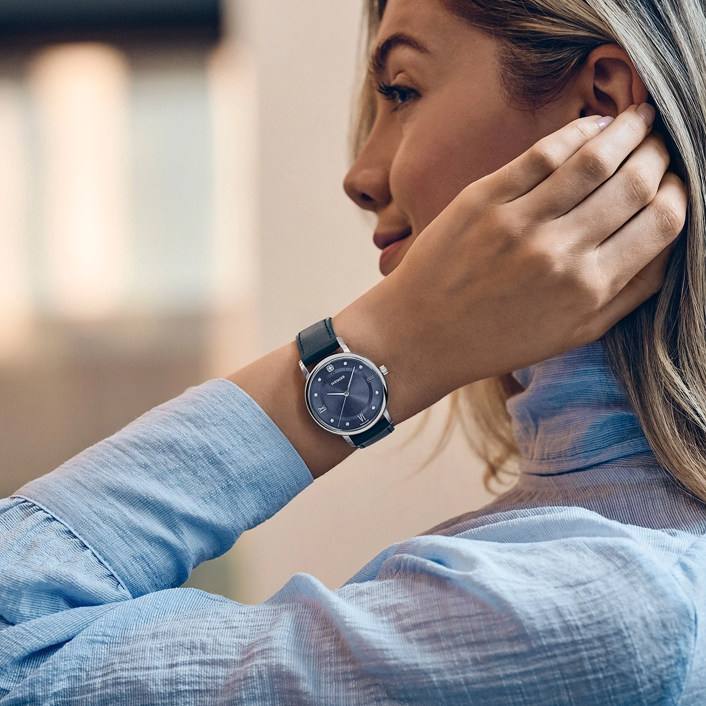 Eine Frau mit einer Uhr am Handgelenk und einer blauen Hemdbluse.