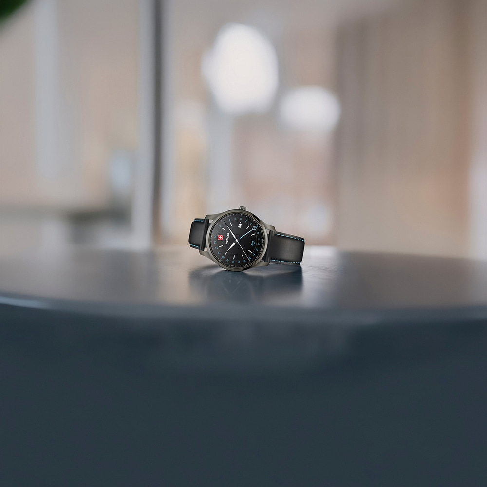 Ein Wenger-Armbanduhr auf einem dunklen Tisch mit unscharfem Hintergrund.