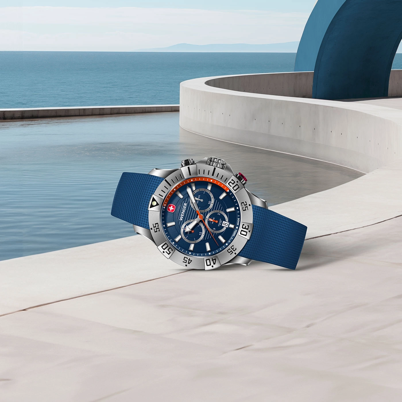 Uhr mit blauem Armband auf einer weißen Oberfläche mit Meerblick und blauem Himmel.