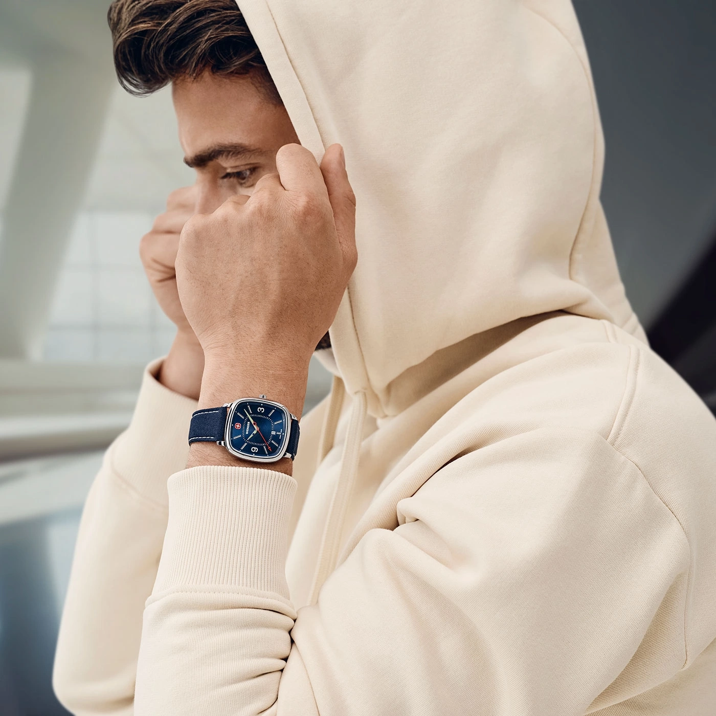 Mann mit Kapuzenpullover und Uhr, die sich die Kapuze über den Kopf zieht.
