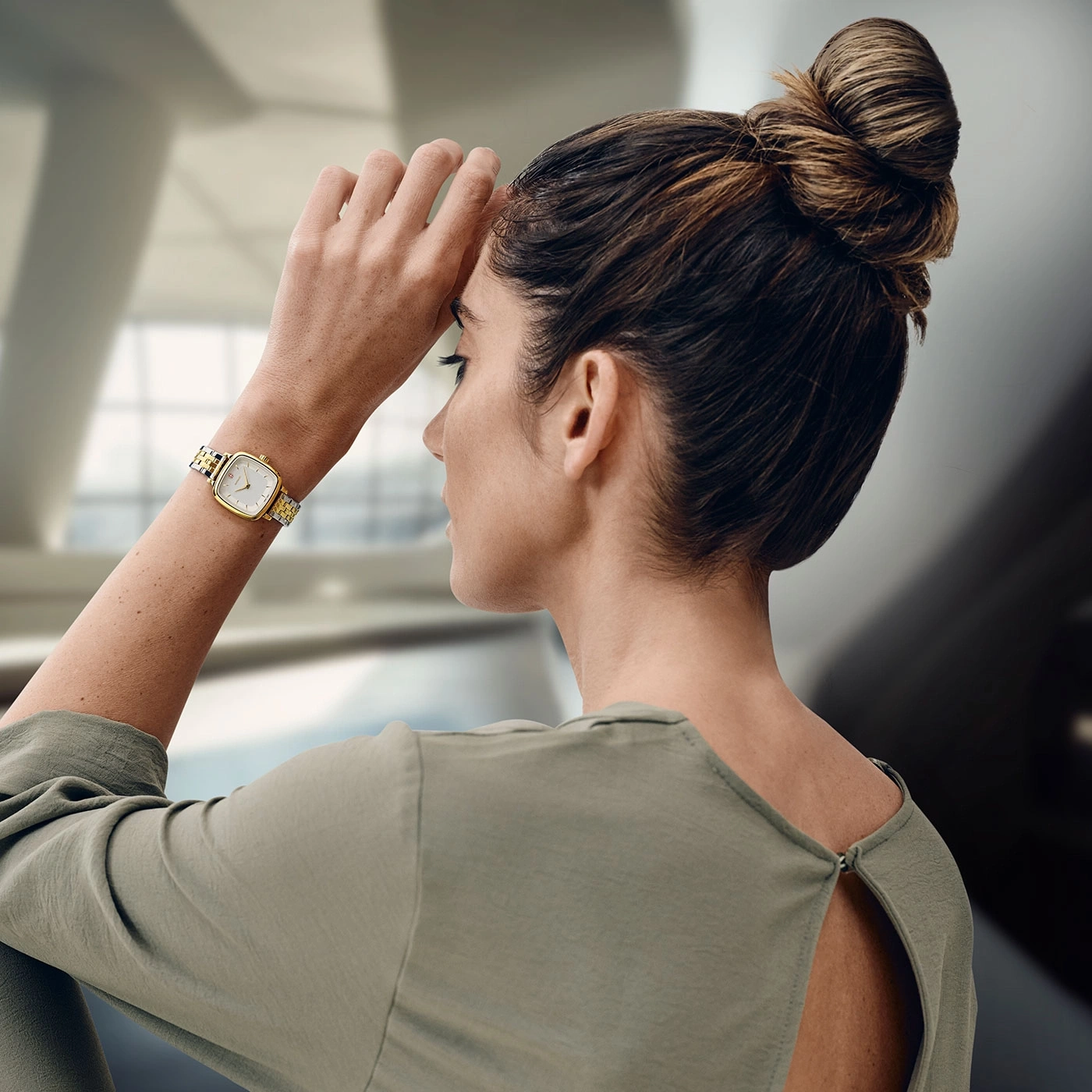 Woman with watch holding hand to forehead, thoughtful, looking away
