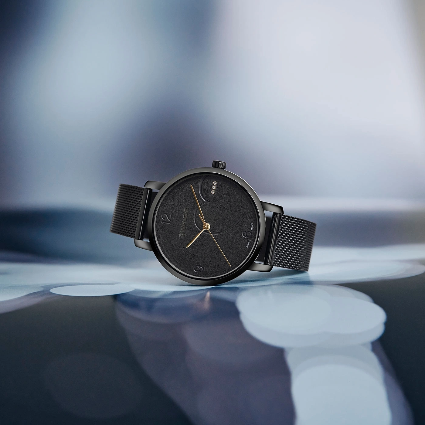 Schwarze Uhr mit goldenen Zeigern und Armband auf glänzendem Hintergrund.