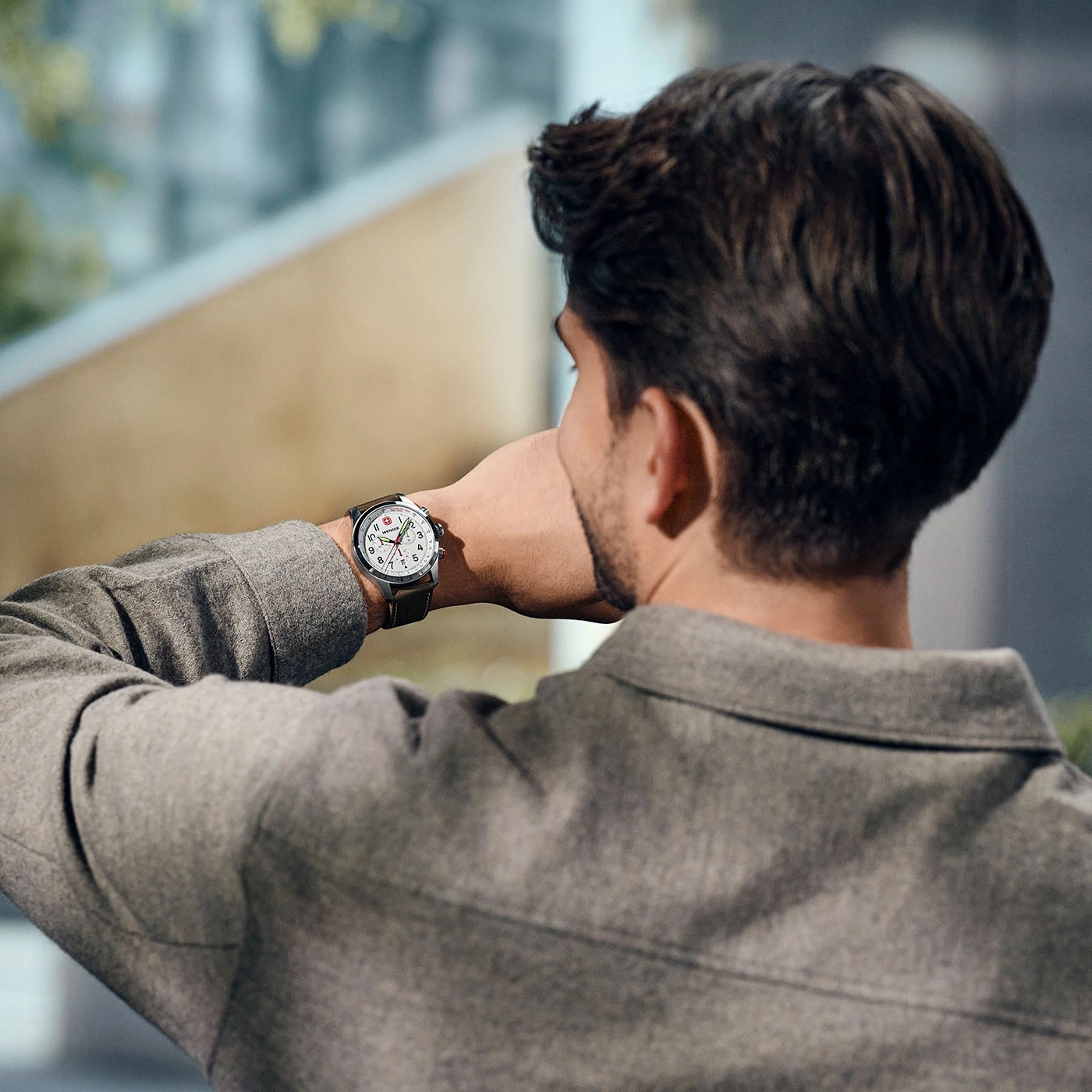 Man looking at his watch. He is wearing a grey shirt. Close-up shot.