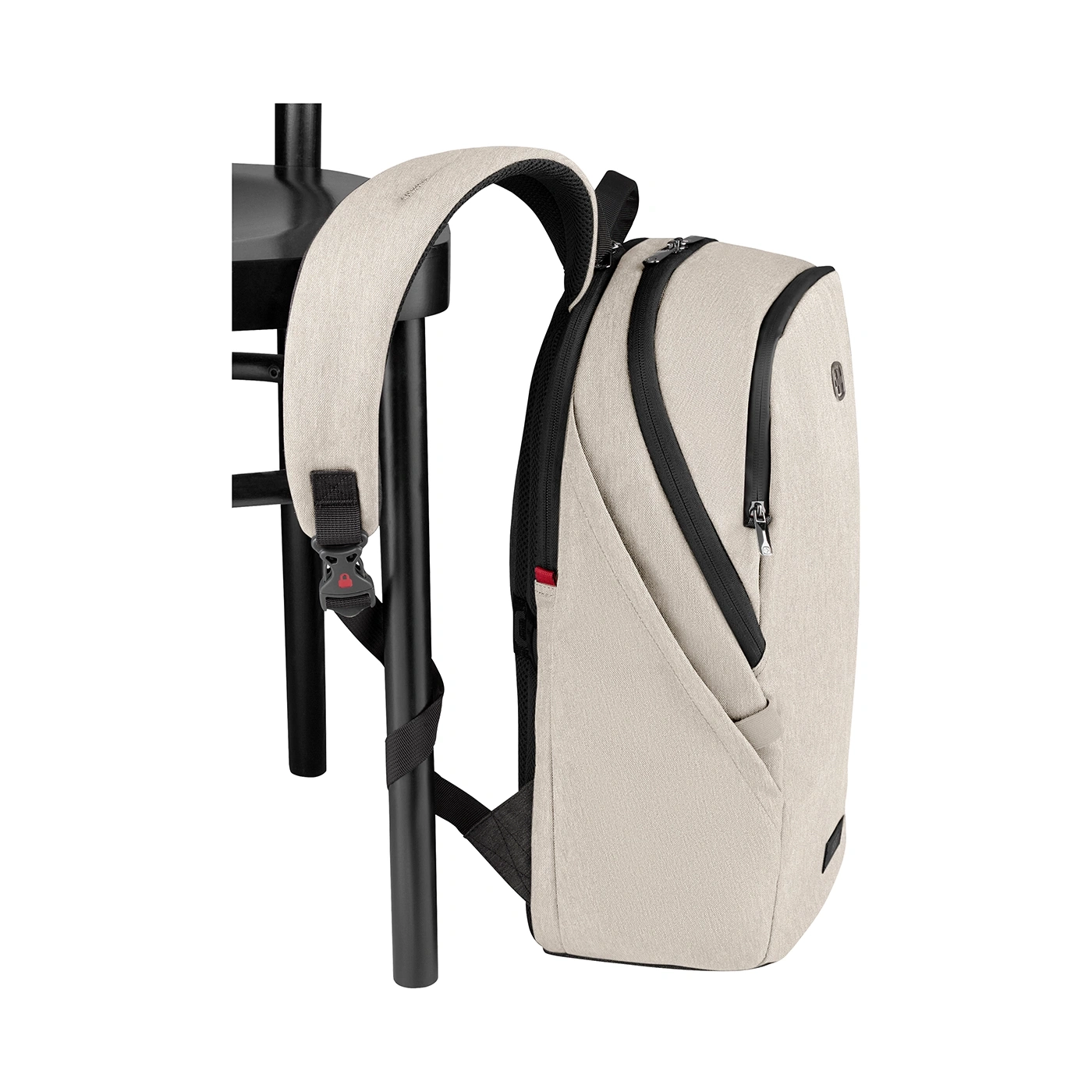 Beige Rucksack an schwarzem Stuhl gelehnt, mit schwarzen Reißverschlüssen und Details.
