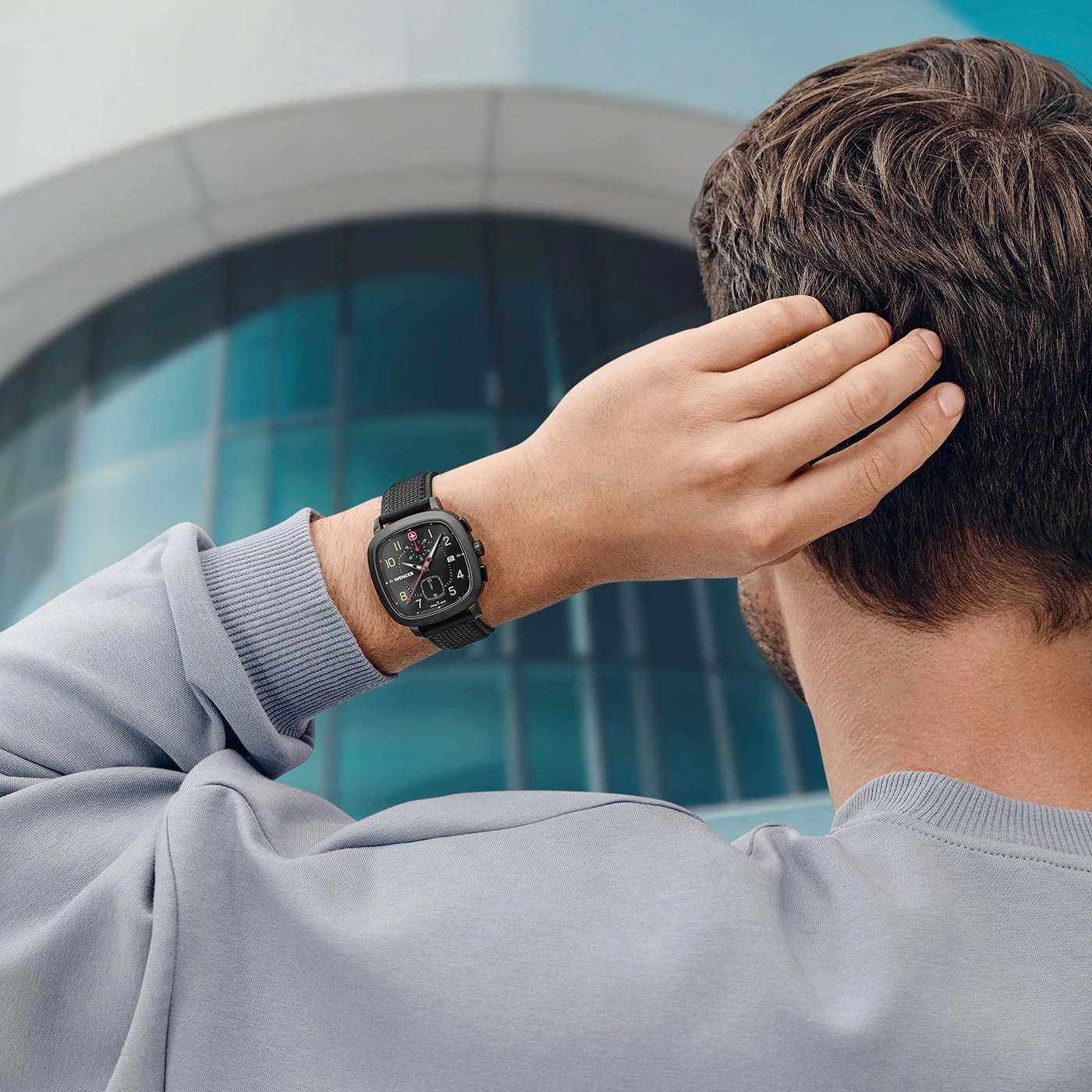 Mann mit Uhr, die sich am Kopf kratzt, vor einem Gebäude