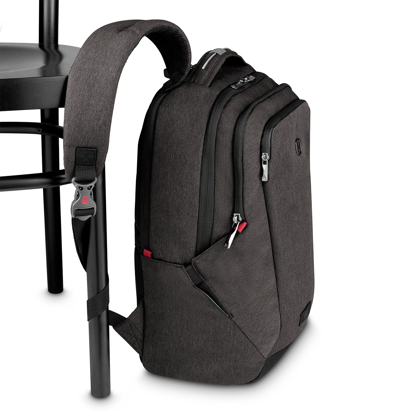 Dunkelgrauer Rucksack, der an einem schwarzen Stuhl hängt, mit roten Akzenten.