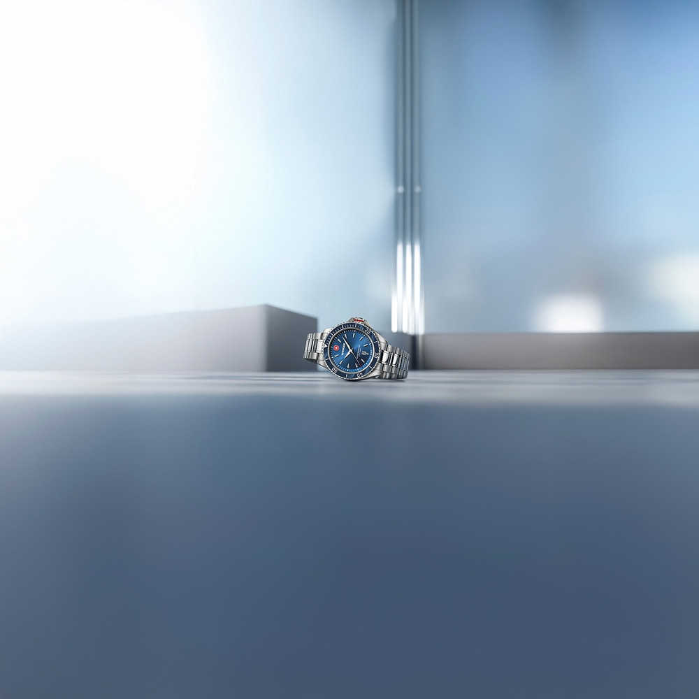 Blue wristwatch on a smooth gray surface with a blurred background.