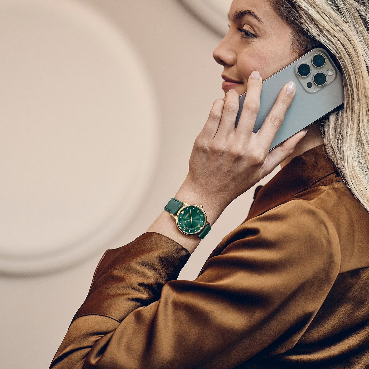 Eine Frau telefoniert mit einem Smartphone und trägt eine grüne Armbanduhr.