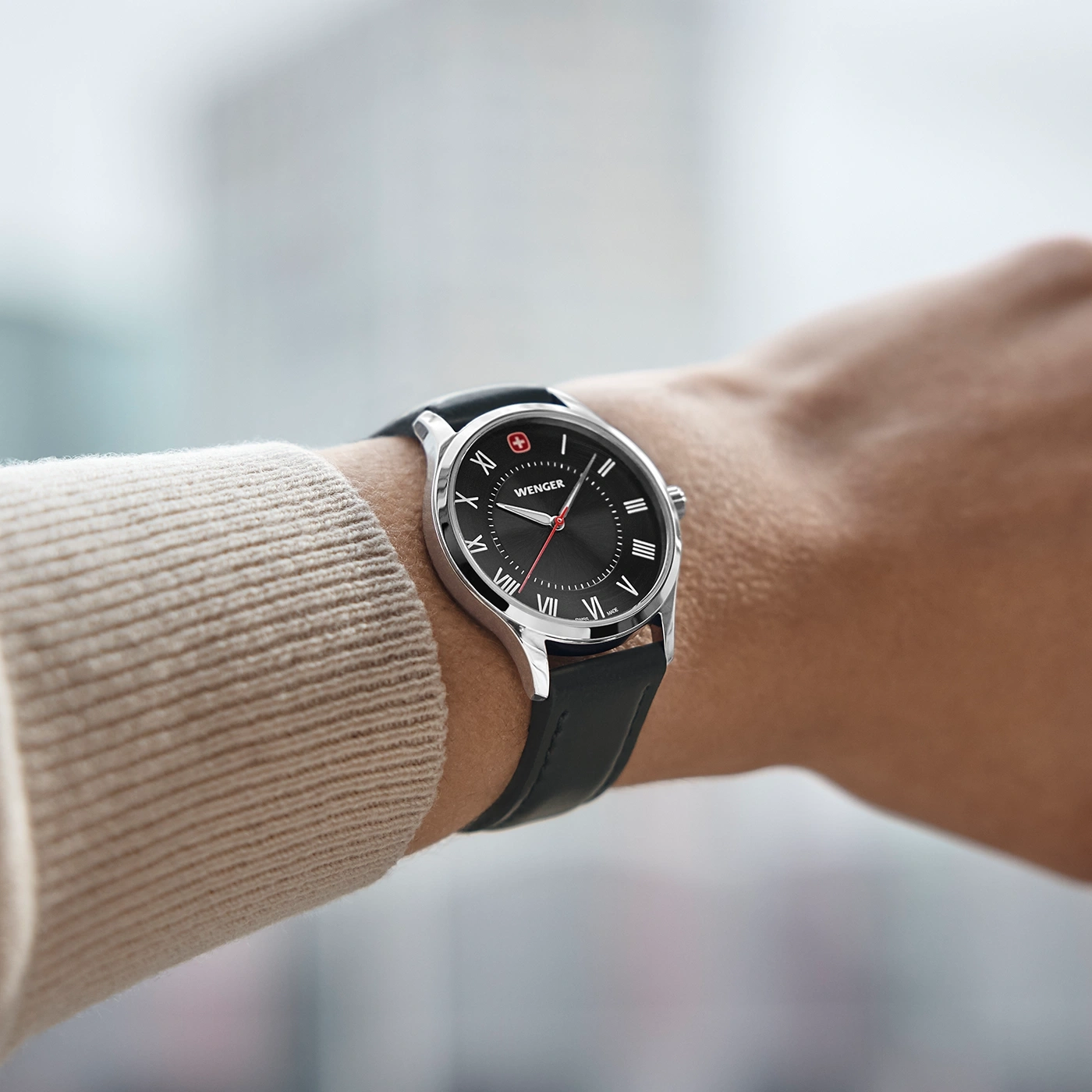 Wenger Uhr am Handgelenk, schwarzes Zifferblatt, Lederarmband, römische Ziffern