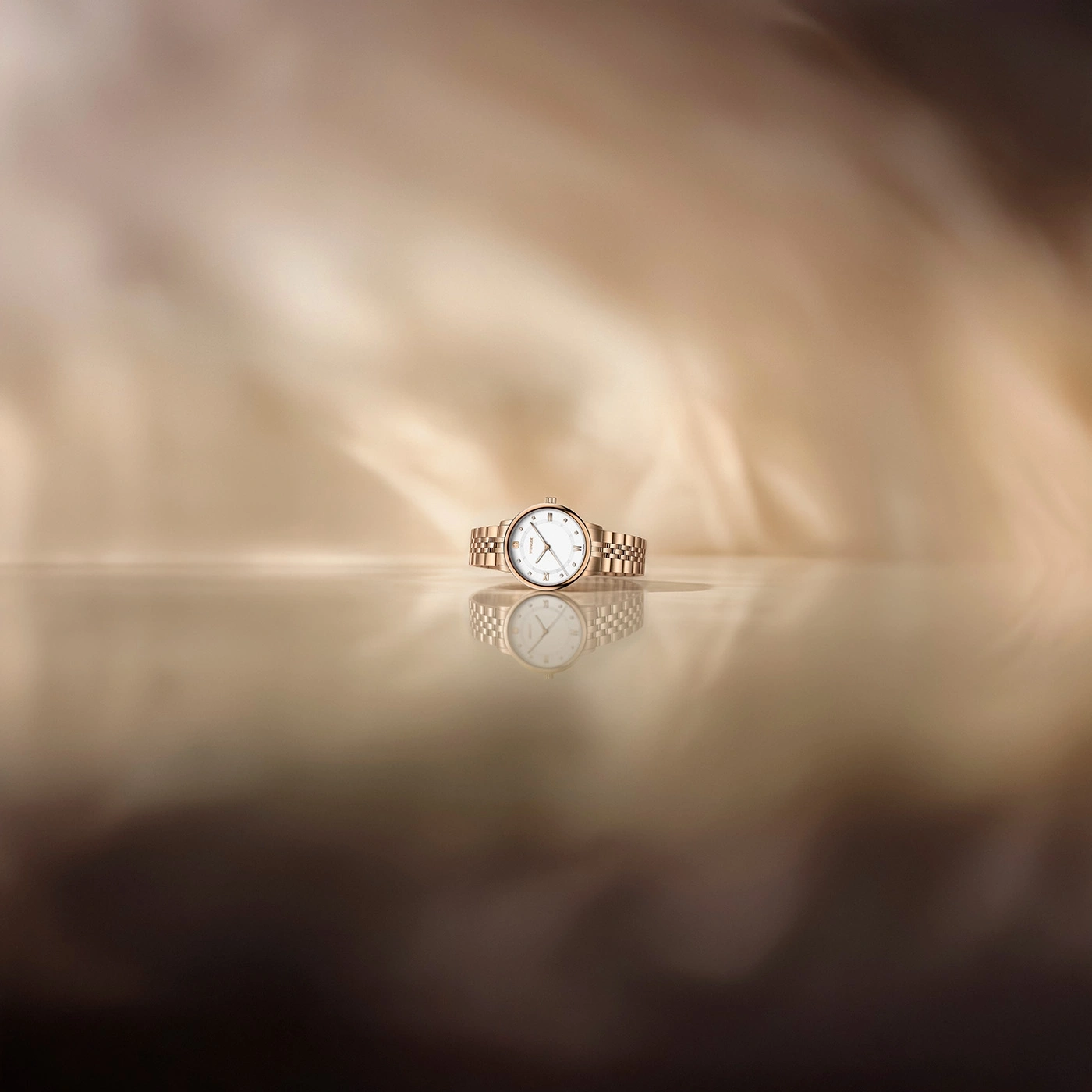 Eine Uhr mit Goldarmband und weißem Zifferblatt auf einer spiegelnden Oberfläche.