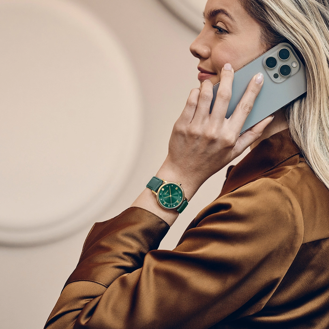 Une femme parle au téléphone portable tout en portant une montre-bracelet verte.