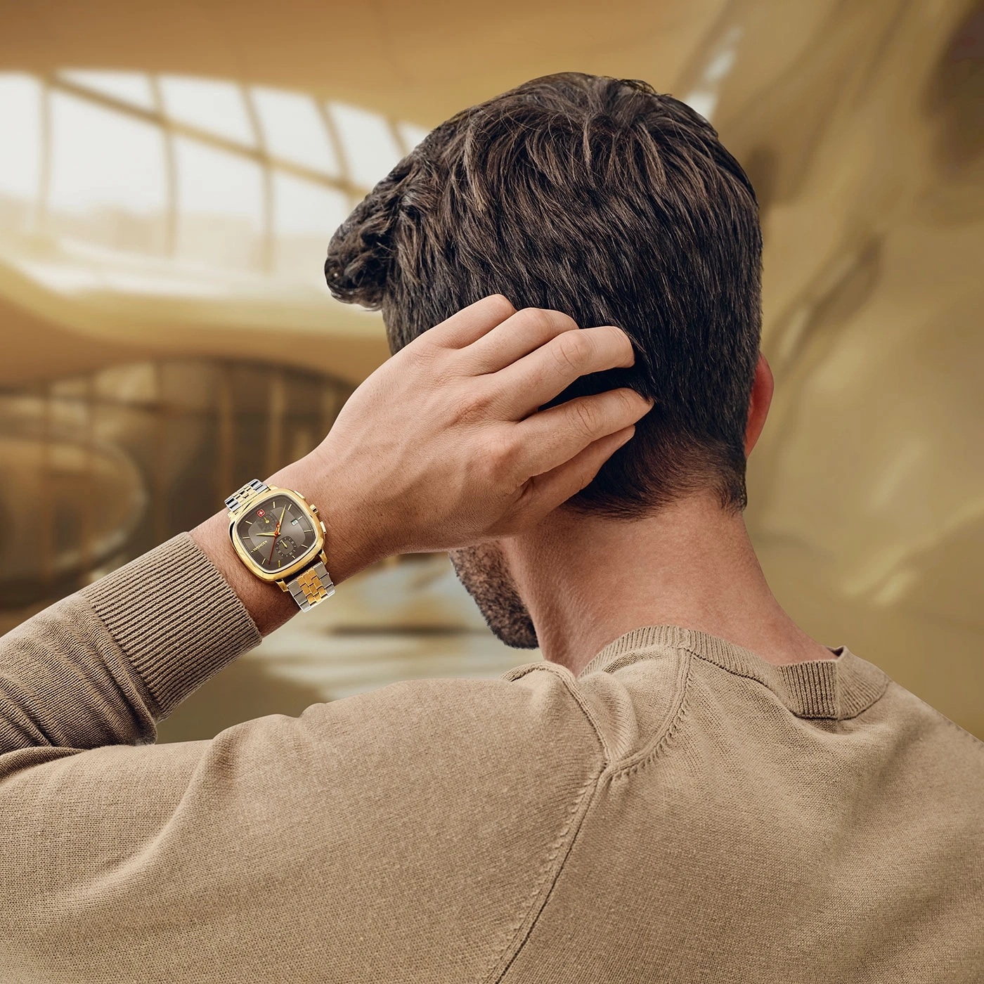 Mann mit Uhr, der sich am Hinterkopf kratzt, in einem modernen Gebäude