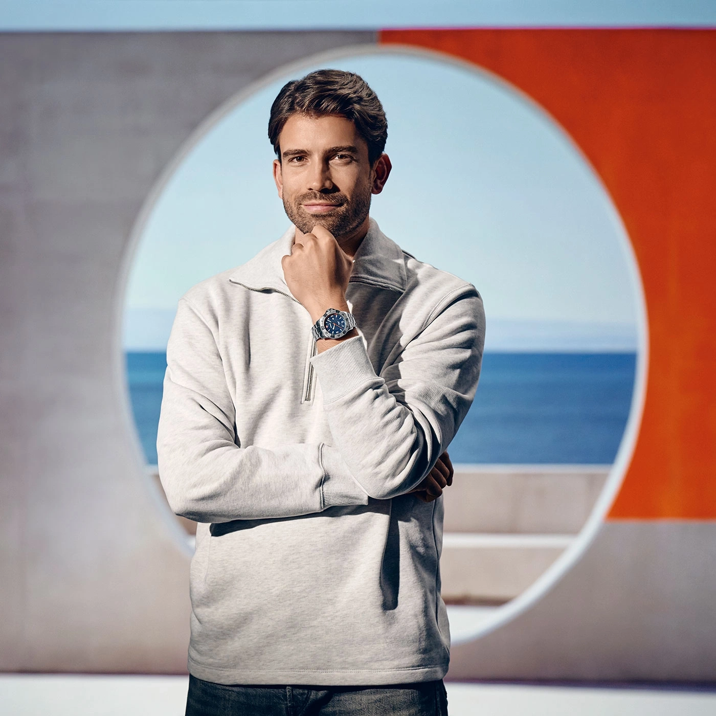 Mann mit Uhr, vor modernem Hintergrund, Meer im Hintergrund, nachdenklich