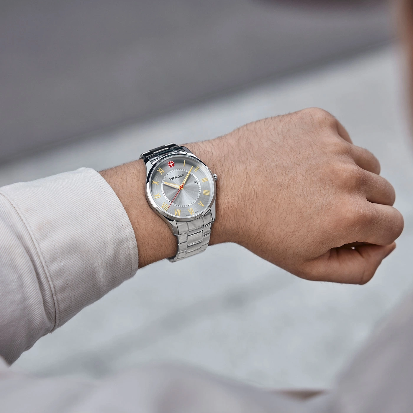 Wristwatch with silver face, gold roman numerals, Wenger brand, stainless steel bracelet